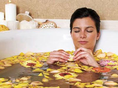 kvinna in bathtub filled with yellow flower petals