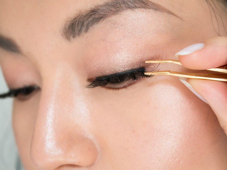 applicering false lash strip to eye with tweezers