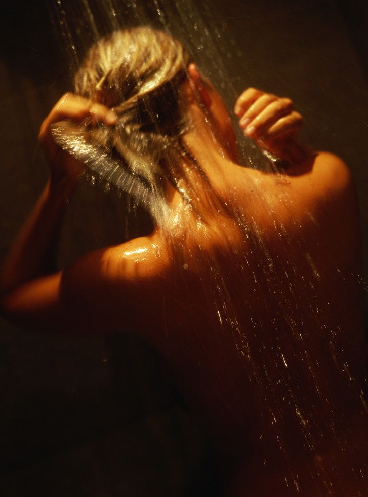 Mladi woman in shower rinsing hair, rear view, close-up