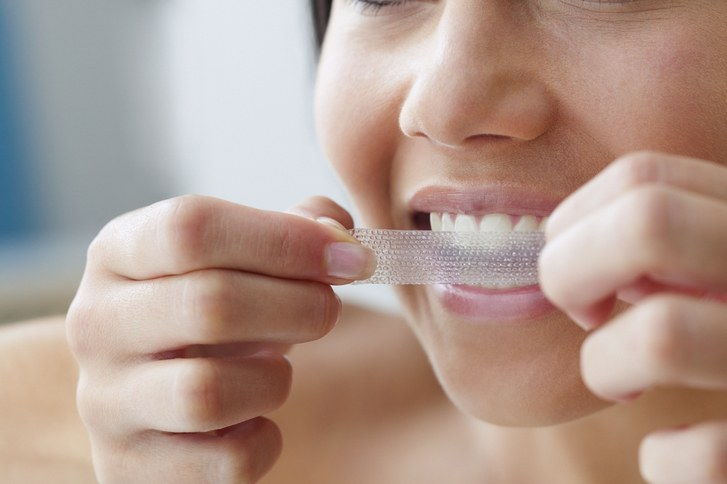 žena using a teeth whitening strip