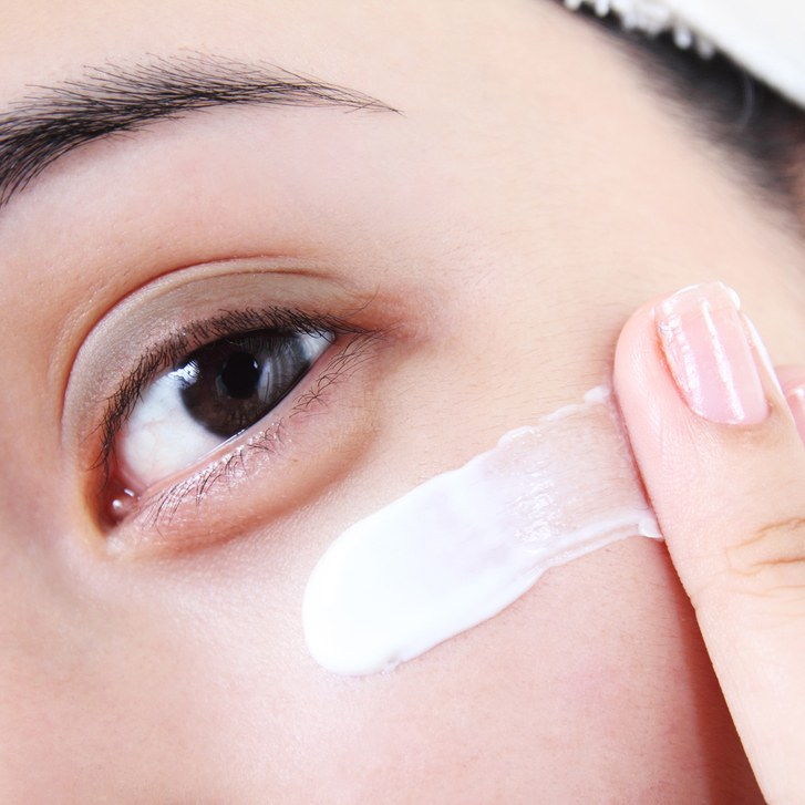 A închide image of woman applying eye cream