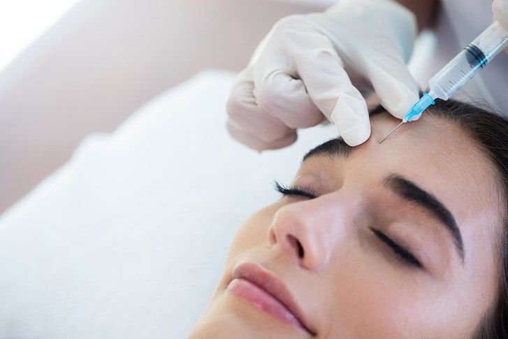 Doctor injecting woman with Botox into the forehead